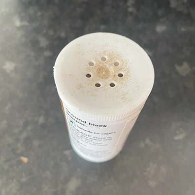 a white plastic pepper jar with tiny holes